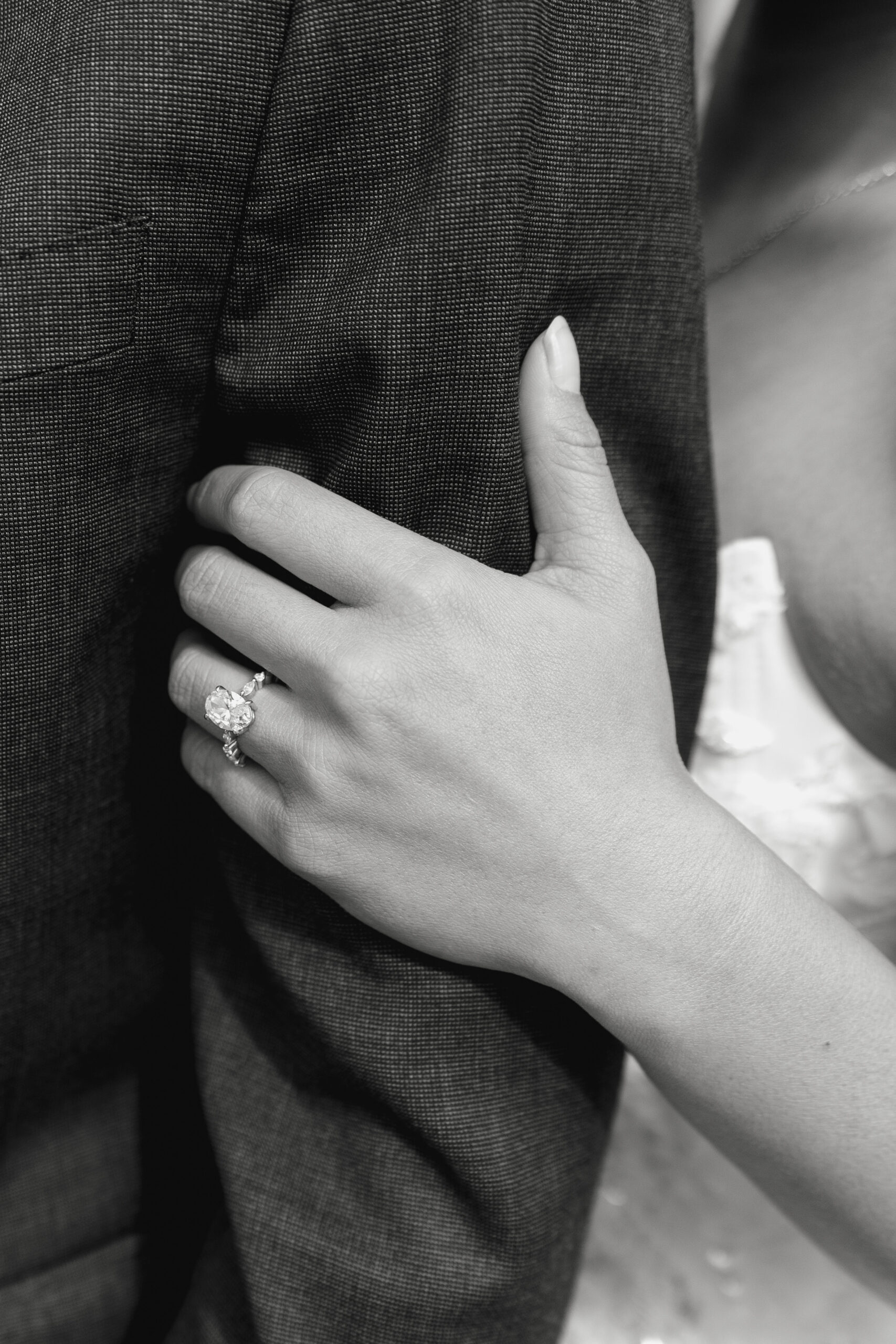 Close-up of Kiana’s hand resting on Matt’s arm, showcasing her engagement ring during their Monserate Winery engagement session.