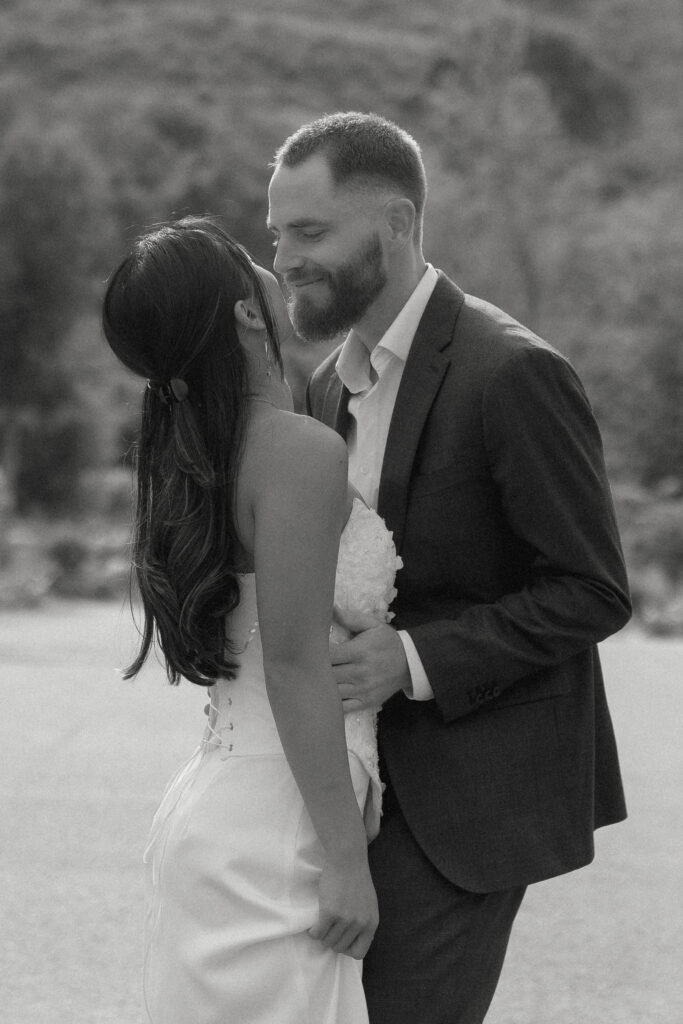 Kiana and Matt sharing a quiet, joyful moment during their Monserate Winery engagement session, with Kiana smiling up at Matt against a backdrop of sunlit hills.